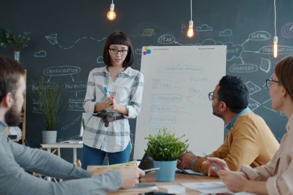 A group of men and woman are sitting in classroom or conference room and talking or training