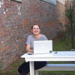 A woman is sitting outside with her laptop computer
