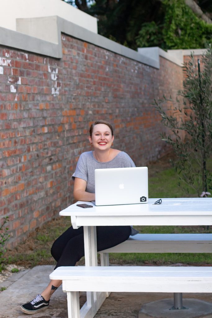 A woman is sitting outside with her laptop computer