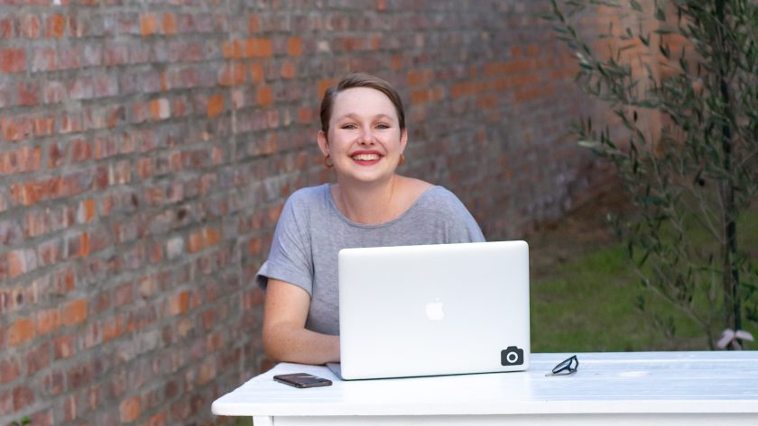 A woman is sitting outside with her laptop computer