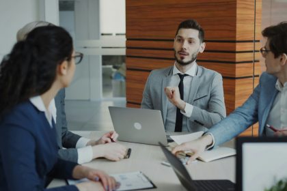 A group of business people are sitting around a desk talking