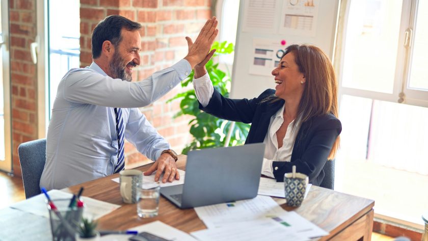 Is Coach Training a Must Have A business man and woman are sitting and giving each other the high-five