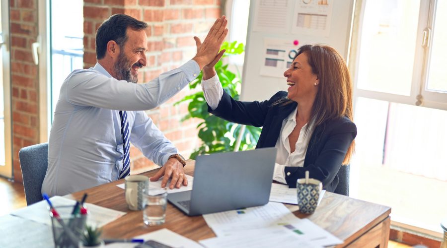 A business man and woman are sitting and giving each other the high-five