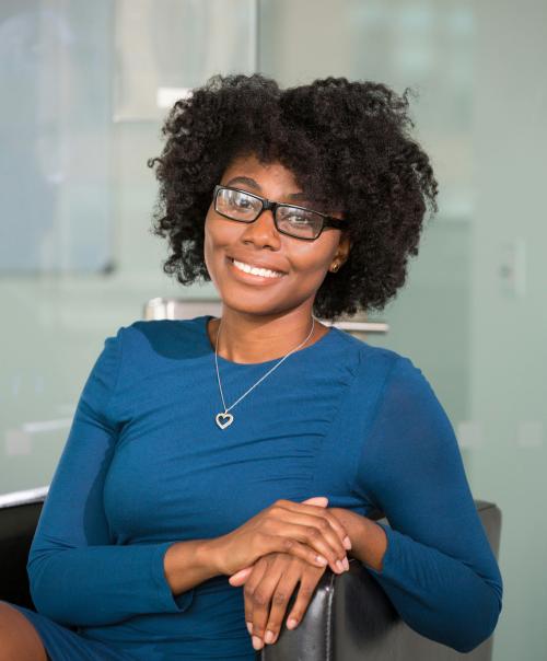 Smiling woman sitting on black chair wearing a blue dress